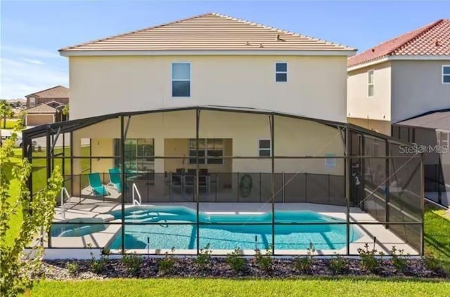 rear view of property featuring a fenced in pool, glass enclosure, and a patio area