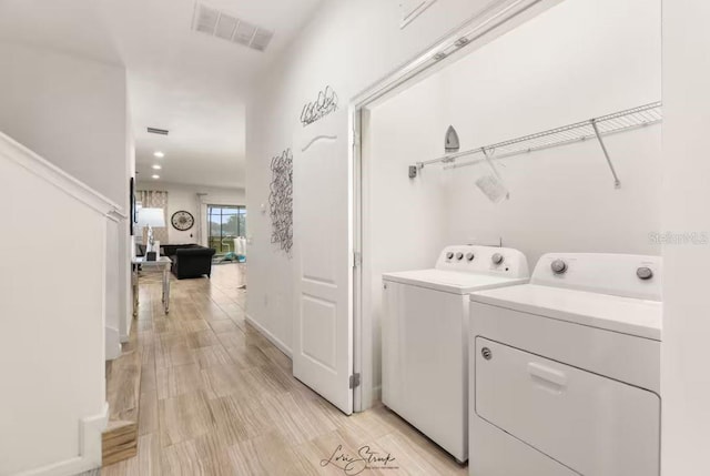 laundry room featuring washer and clothes dryer and light hardwood / wood-style floors