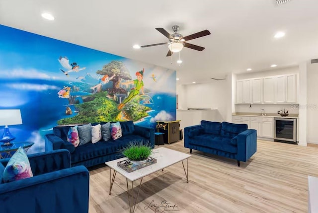 living room with wine cooler, ceiling fan, wet bar, and light hardwood / wood-style flooring