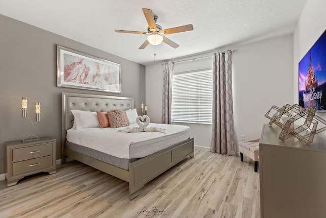 bedroom featuring ceiling fan, light hardwood / wood-style flooring, and a textured ceiling