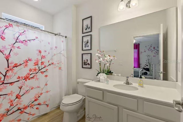 bathroom with vanity, toilet, curtained shower, and hardwood / wood-style floors