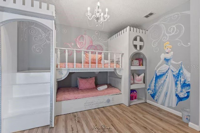 bedroom featuring an inviting chandelier, hardwood / wood-style floors, and a textured ceiling