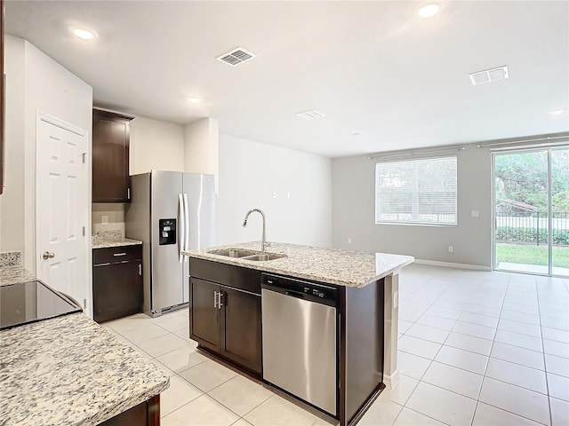 kitchen featuring a center island with sink, stainless steel appliances, sink, dark brown cabinets, and light tile patterned floors