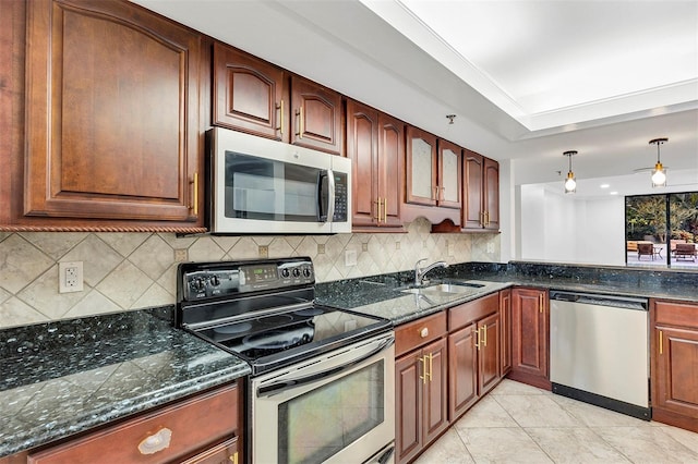 kitchen with sink, appliances with stainless steel finishes, hanging light fixtures, a tray ceiling, and dark stone counters