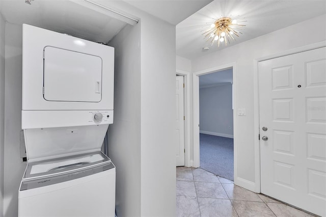 washroom featuring light tile patterned floors, stacked washer and clothes dryer, and a chandelier