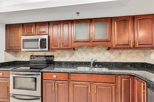 kitchen with dark stone countertops, sink, decorative backsplash, and appliances with stainless steel finishes