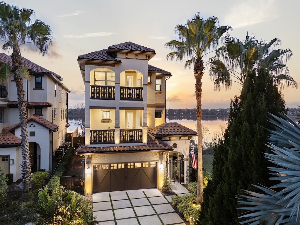 mediterranean / spanish-style home with a garage, a balcony, and a water view