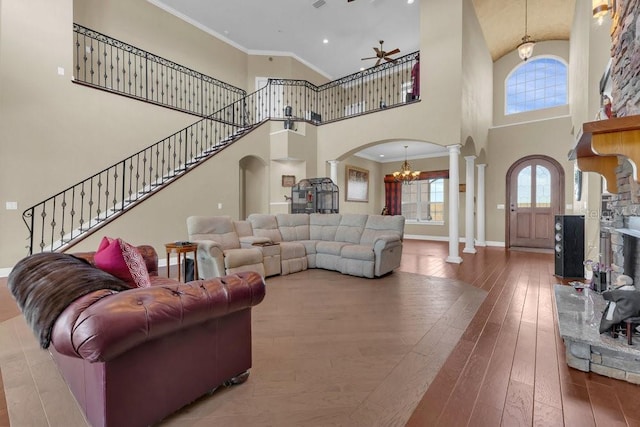 living room featuring hardwood / wood-style floors, crown molding, decorative columns, and a high ceiling