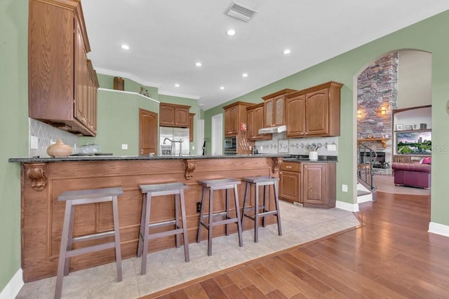 kitchen with decorative backsplash, light hardwood / wood-style flooring, ornamental molding, and kitchen peninsula