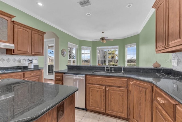 kitchen with a healthy amount of sunlight, sink, dark stone counters, and dishwasher