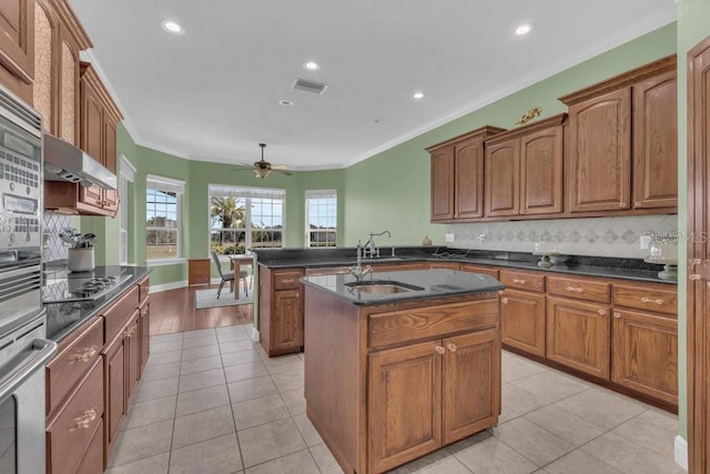 kitchen featuring a kitchen island with sink, sink, crown molding, and light tile patterned flooring