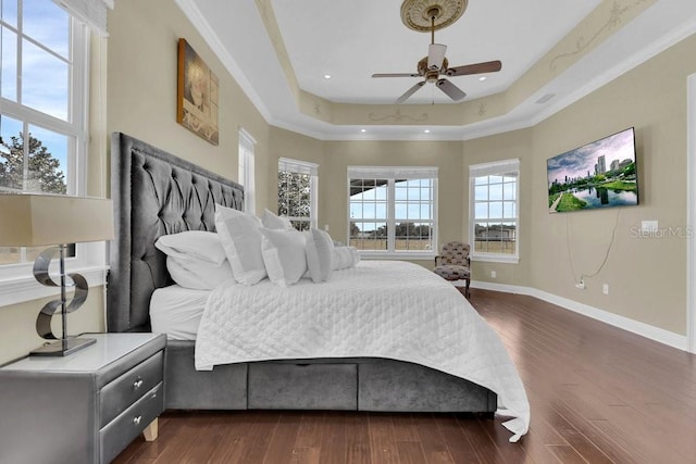 bedroom featuring ceiling fan, a tray ceiling, and dark hardwood / wood-style flooring