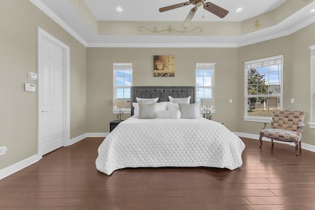 bedroom featuring a raised ceiling, dark wood-type flooring, and ceiling fan