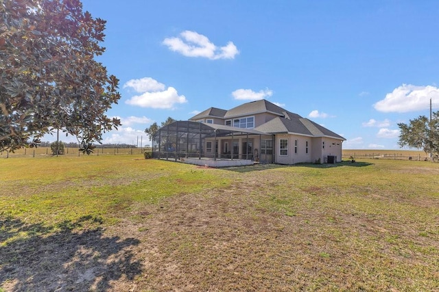 rear view of house featuring a rural view, a yard, and glass enclosure