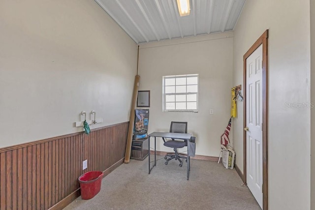 carpeted home office featuring wood walls