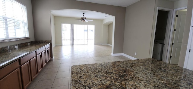 kitchen featuring ceiling fan, dark stone countertops, and light tile patterned floors