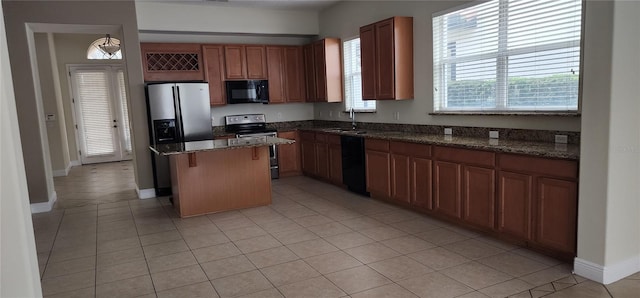 kitchen with sink, a breakfast bar area, black appliances, a kitchen island, and dark stone counters