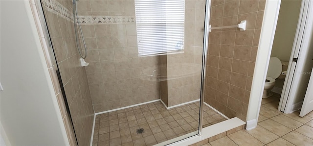 bathroom featuring tile patterned floors, toilet, and a tile shower