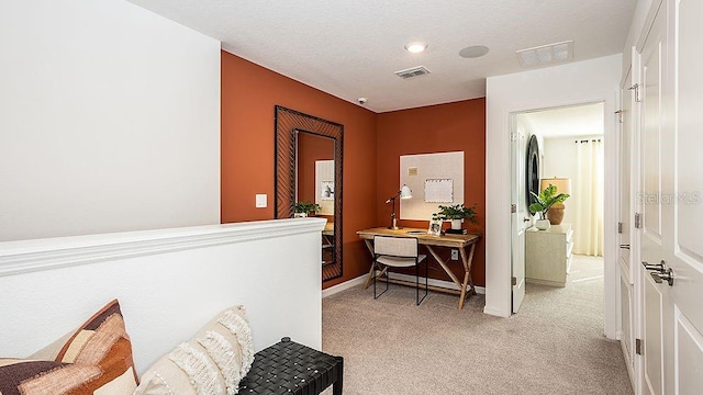 hall featuring light carpet and a textured ceiling