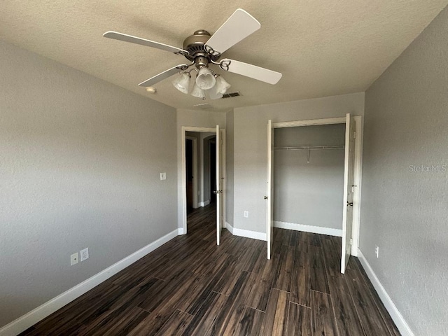 unfurnished bedroom with ceiling fan, a textured ceiling, dark hardwood / wood-style flooring, and a closet