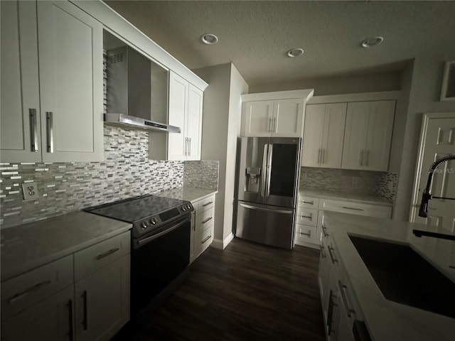 kitchen with wall chimney exhaust hood, sink, white cabinetry, stainless steel fridge, and electric stove