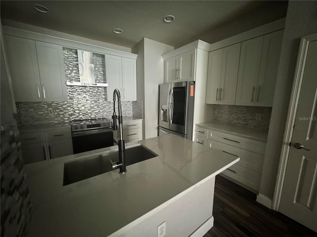 kitchen featuring white cabinets, dark hardwood / wood-style flooring, decorative backsplash, stainless steel appliances, and wall chimney range hood