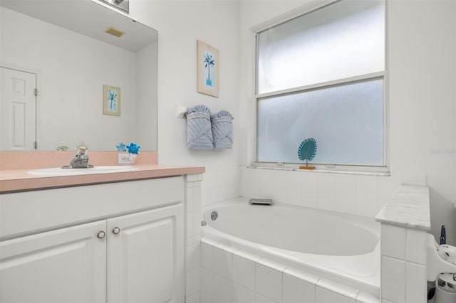 bathroom with vanity and tiled bath