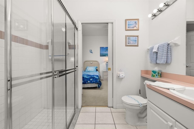 bathroom featuring vanity, a shower with door, tile patterned floors, and toilet