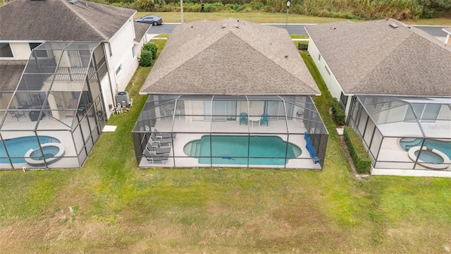 view of pool featuring an in ground hot tub, a lawn, glass enclosure, and a patio