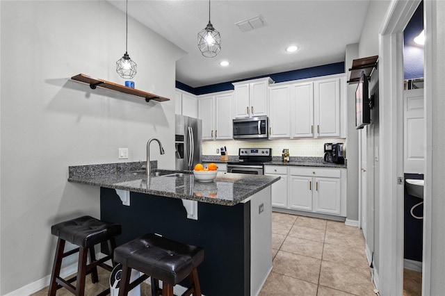 kitchen with appliances with stainless steel finishes, a kitchen breakfast bar, kitchen peninsula, and white cabinets