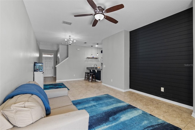 living room featuring sink, ceiling fan with notable chandelier, and wooden walls