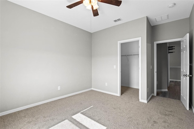 unfurnished bedroom featuring ceiling fan, a closet, a spacious closet, and light carpet