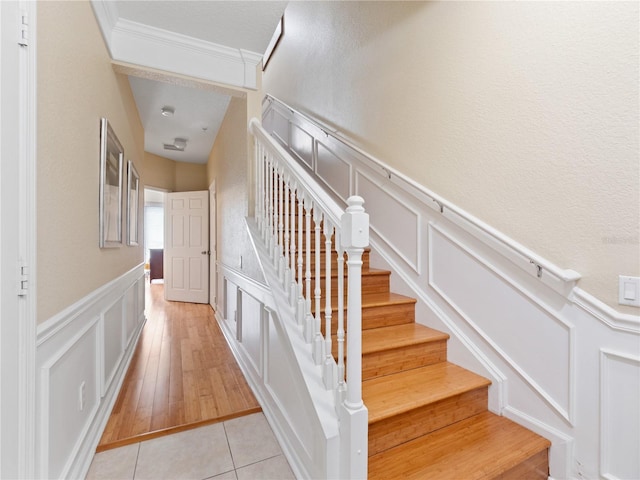 stairway with ornamental molding and tile patterned flooring