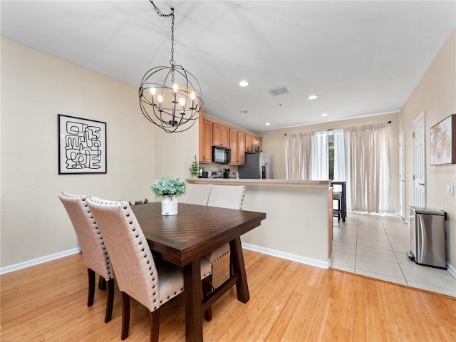 dining space with light hardwood / wood-style floors and a notable chandelier