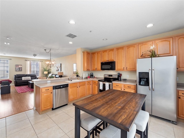 kitchen with light tile patterned flooring, appliances with stainless steel finishes, sink, and kitchen peninsula