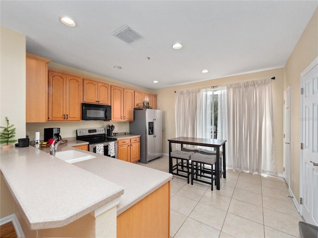 kitchen with appliances with stainless steel finishes, kitchen peninsula, sink, and light tile patterned floors