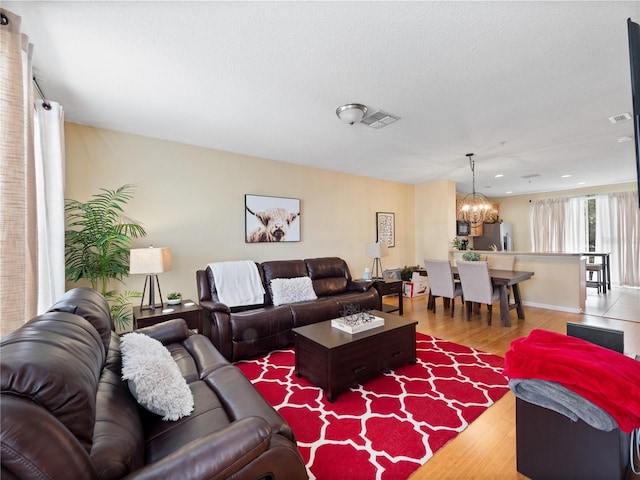 living room with a notable chandelier, light hardwood / wood-style floors, and a textured ceiling