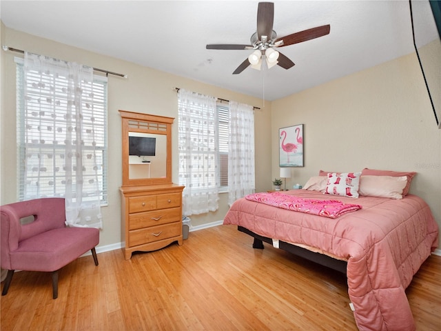 bedroom featuring multiple windows, hardwood / wood-style flooring, and ceiling fan