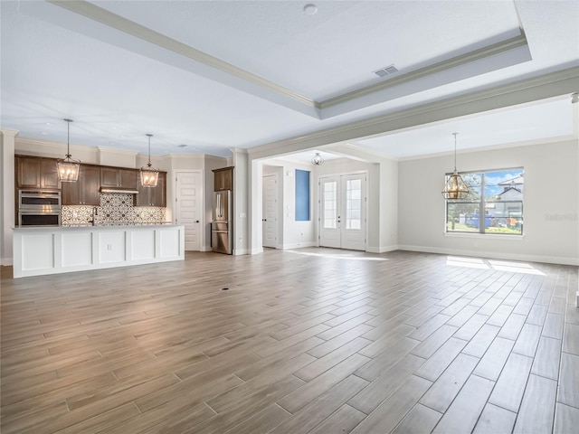 unfurnished living room featuring dark hardwood / wood-style flooring, ornamental molding, a raised ceiling, and french doors