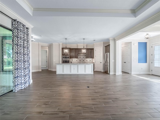 unfurnished living room with sink, a notable chandelier, ornamental molding, and dark hardwood / wood-style floors