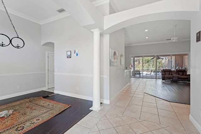 entrance foyer featuring crown molding, ceiling fan, light tile patterned floors, and ornate columns