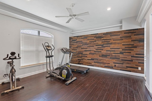 workout area with ceiling fan, an accent wall, baseboards, and dark wood-style flooring