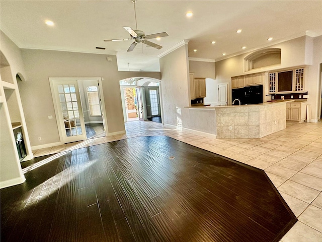 interior space with arched walkways, crown molding, light wood finished floors, a ceiling fan, and baseboards