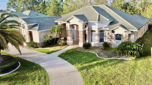 view of front of house with stone siding, a front lawn, a tile roof, and stucco siding