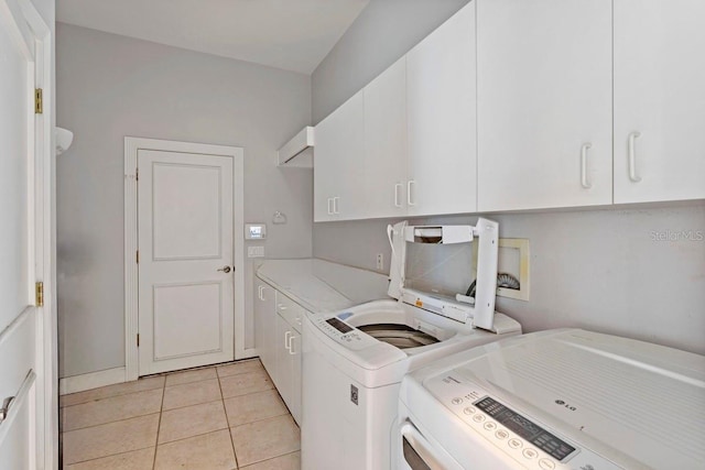 laundry area with light tile patterned floors, washing machine and dryer, and cabinet space