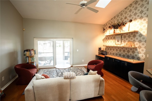 living room featuring wood-type flooring, vaulted ceiling with skylight, and ceiling fan