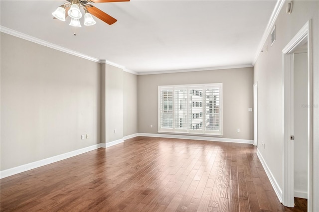 unfurnished room with crown molding, visible vents, a ceiling fan, wood finished floors, and baseboards