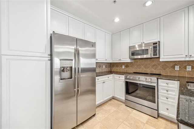 kitchen with tasteful backsplash, appliances with stainless steel finishes, white cabinets, and dark stone countertops