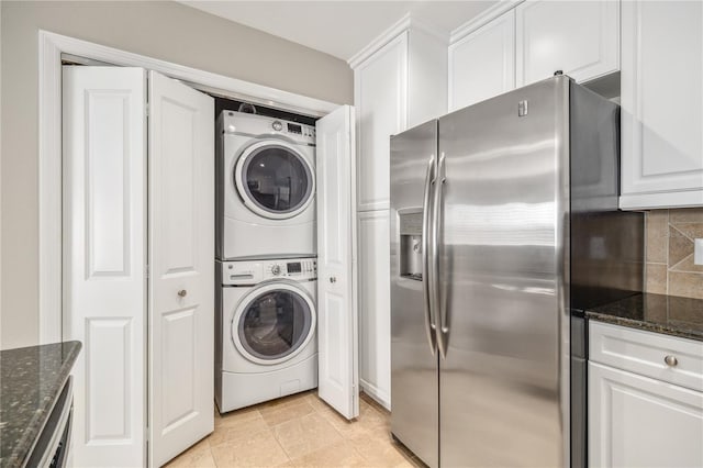 clothes washing area with light tile patterned floors, laundry area, and stacked washing maching and dryer