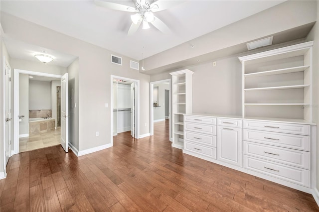 interior space featuring baseboards, visible vents, wood finished floors, a walk in closet, and a closet